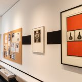 Interior of art gallery with framed orange and black print of two squashes.