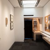 Interior of art gallery showing cream and black art deco style metal sculpture on wall.