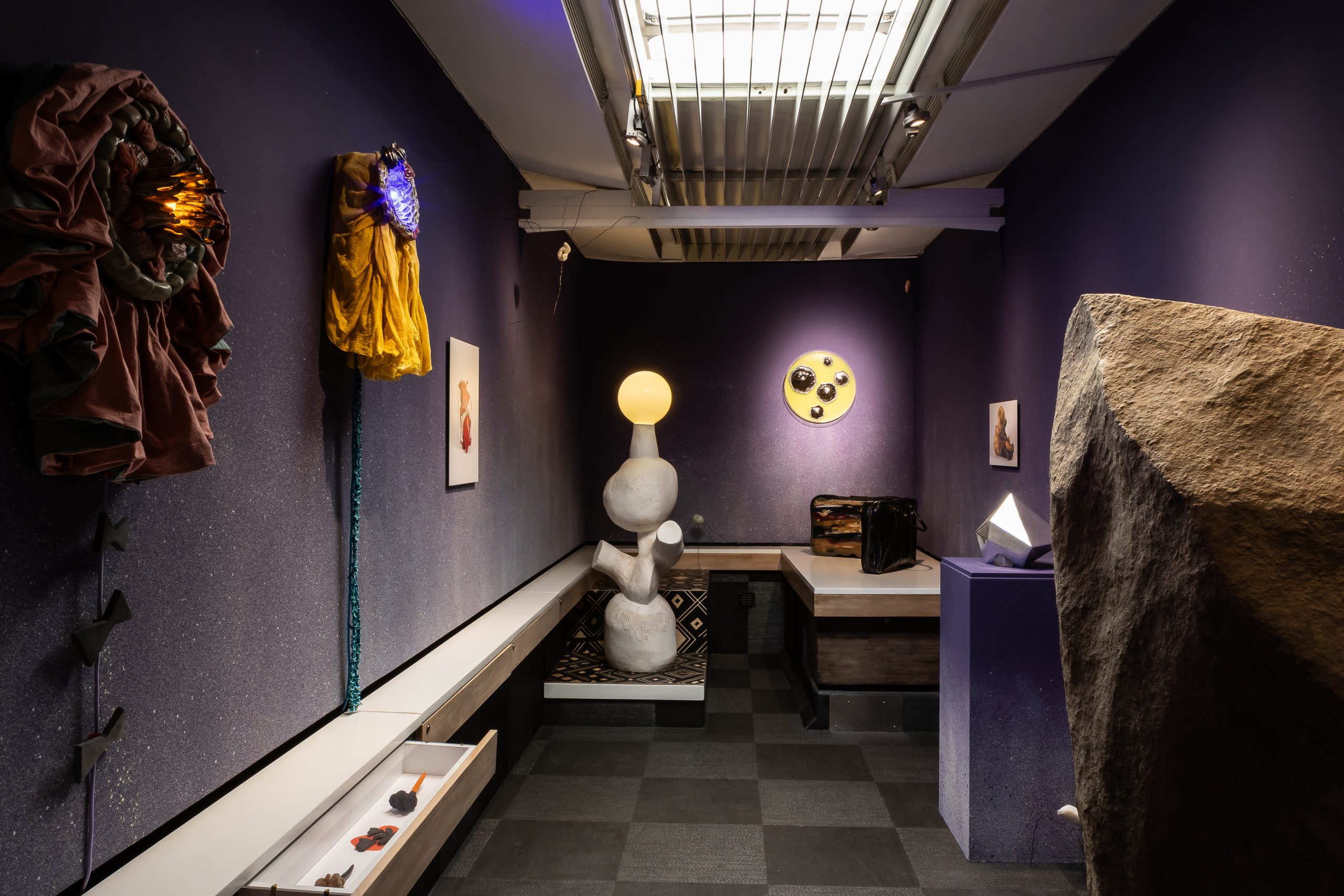 Interior view of Travelling Gallery with purple walls and several sculptures in the space,