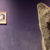 Interior of art gallery with large paper mache rock in foreground