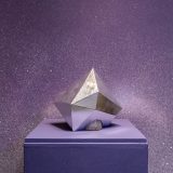 Interior of art gallery with purple sparkly wall and silver geometric crystal shaped sculpture on a plinth