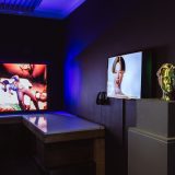 Interior of art gallery with black walls and multiple bright tv screens